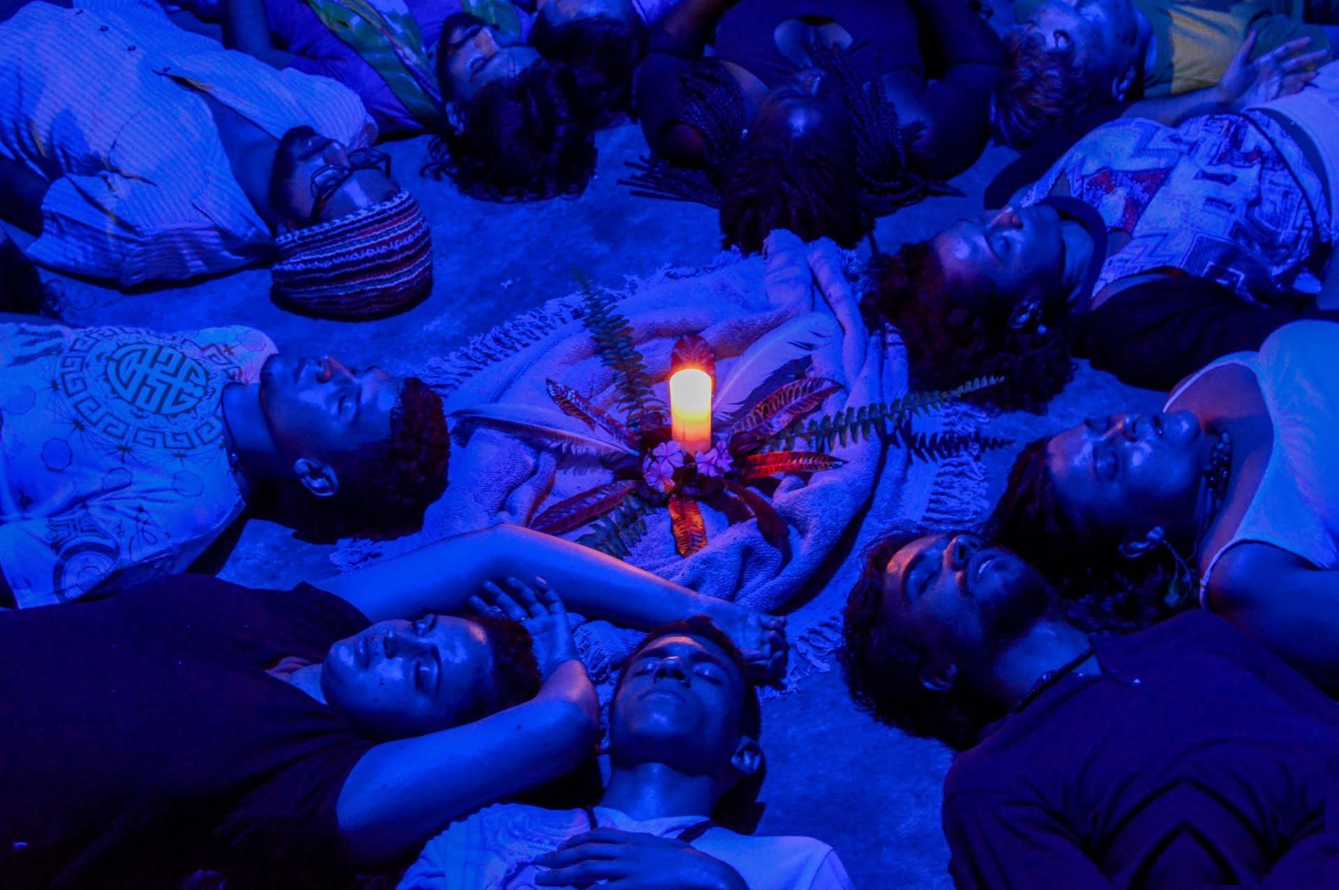 Homens deitados em círculo durante vivência noturna, com vela ao centro
